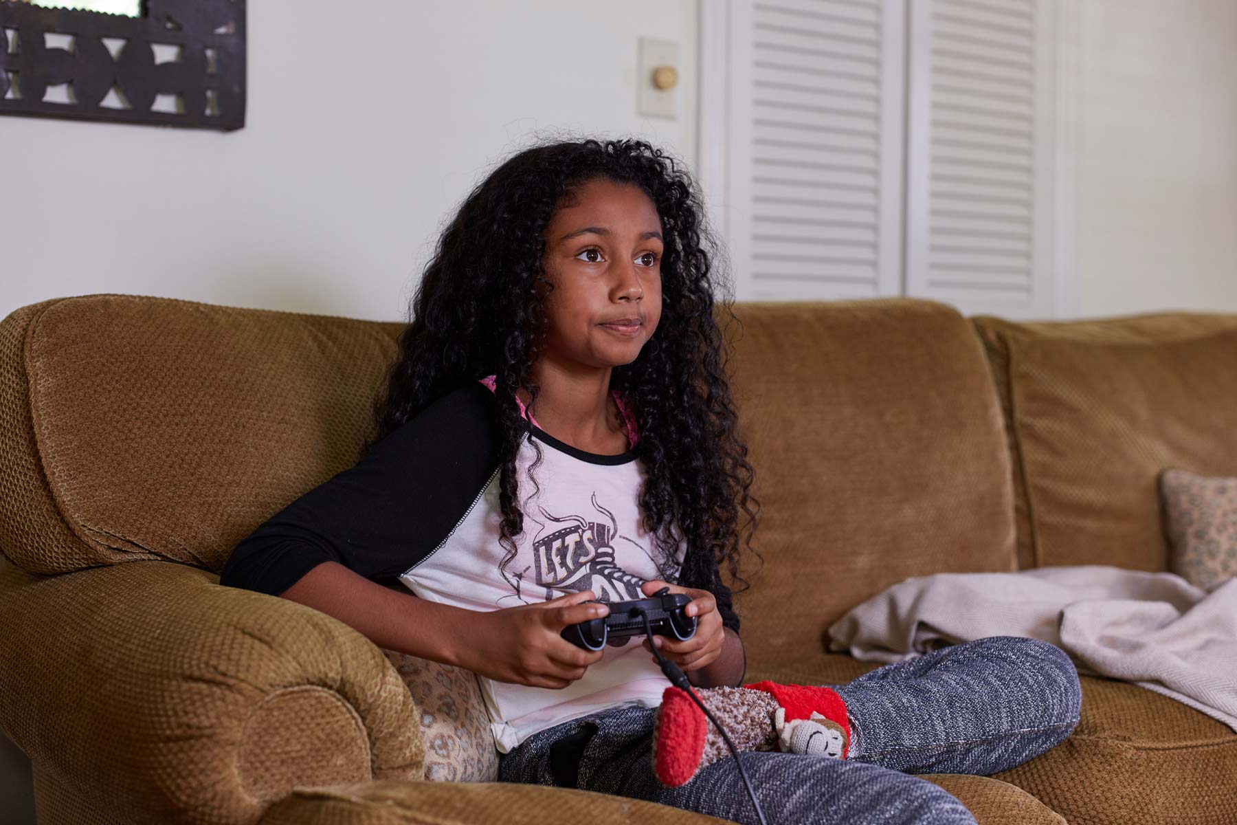 girl sitting on couch playing video games